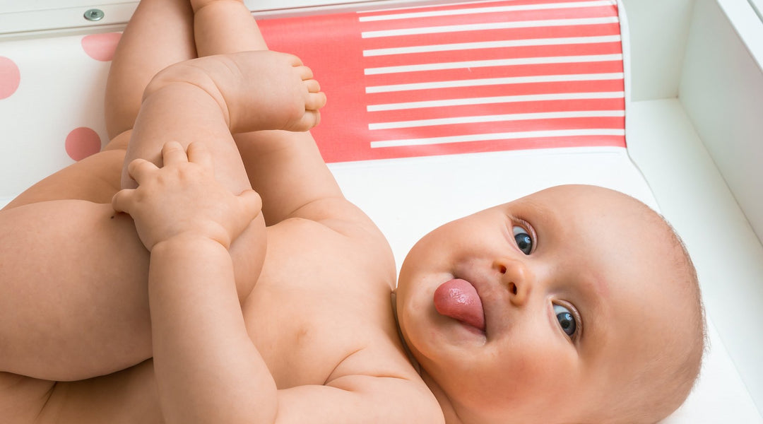 Cute baby on a changing table sticking out tongue