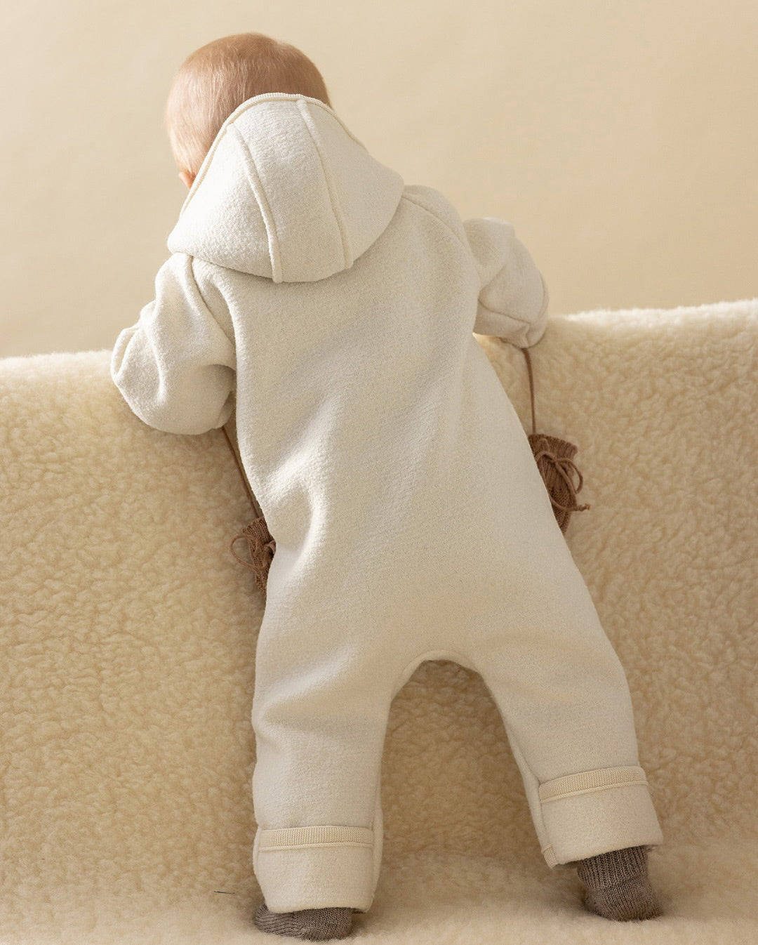 baby in wool snowsuit back